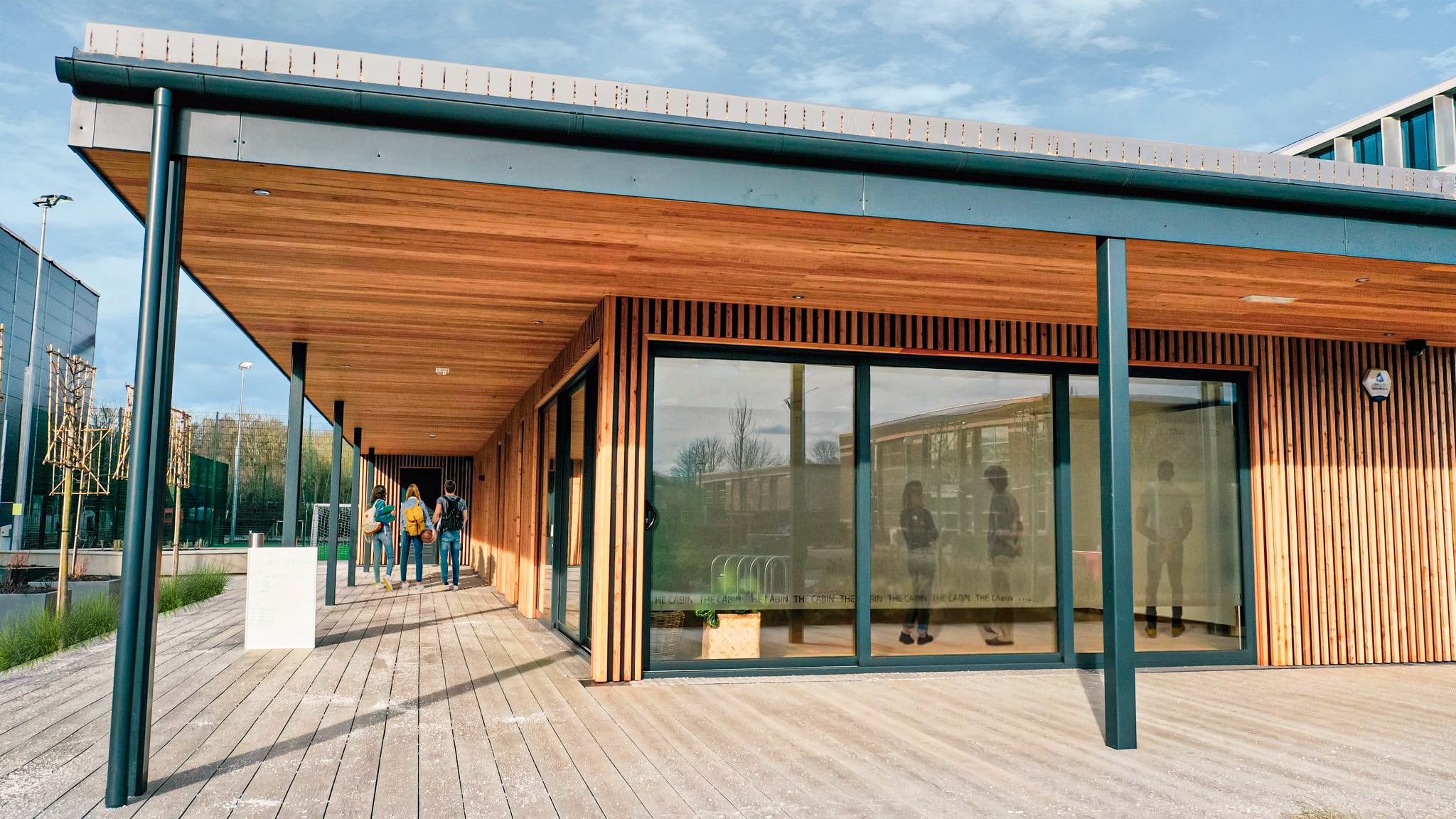 A modular timber building with large glass windows and a canopy