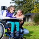 Disabled child with her carer in a park